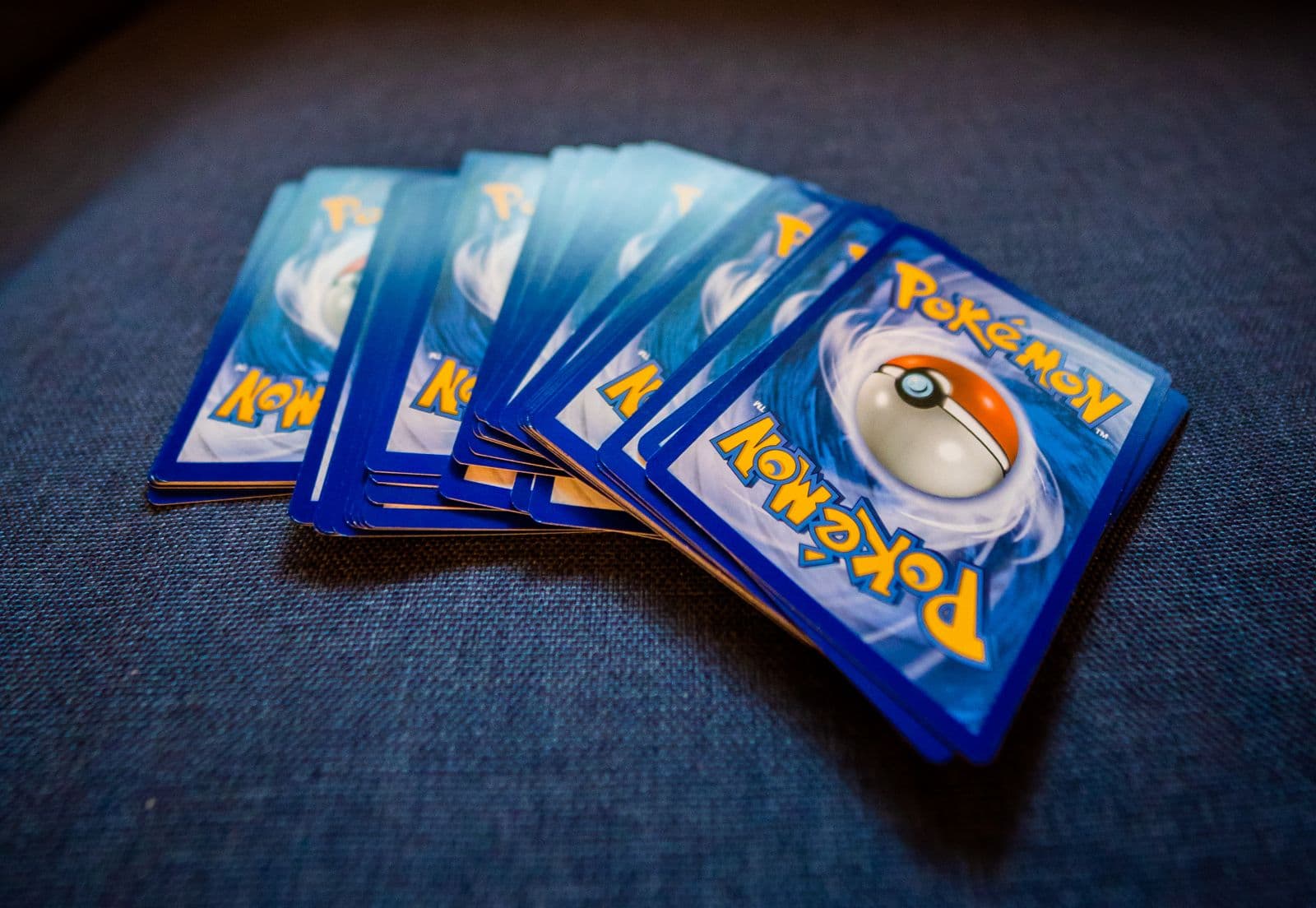 A fanned stack of Pokémon trading cards showing their blue Poké Ball backs